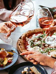 Gezellige toast met pizza en seizoensgerechten tijdens een groepsdiner.