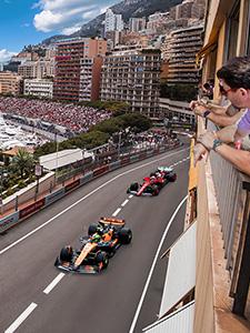 Formule 1-auto’s razen door de straten van Monaco terwijl fans toekijken vanaf de balkons.