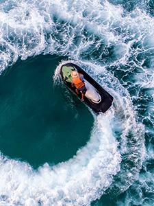 Persoon op een jetski maakt een scherpe bocht op helder turquoise water.
