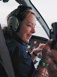 Lachende gast met headset tijdens een panoramische helikoptervlucht.