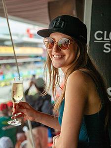 Gast geniet van een glas champagne met uitzicht op de race vanuit de VIP-zone.