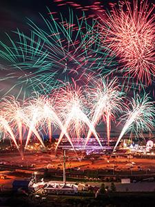 Kleurrijk vuurwerk verlicht de nachtelijke hemel boven de showlocatie.