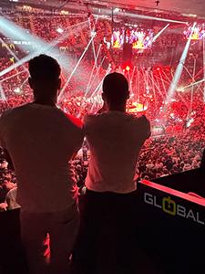 Concertpubliek met podiumlichten in een energieke nachtsfeer.