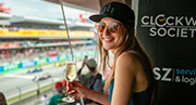 Una emocionada fan femenina de Fórmula 1 con una copa de champán en la tribuna Global-Tickets Mavericks Club durante una carrera